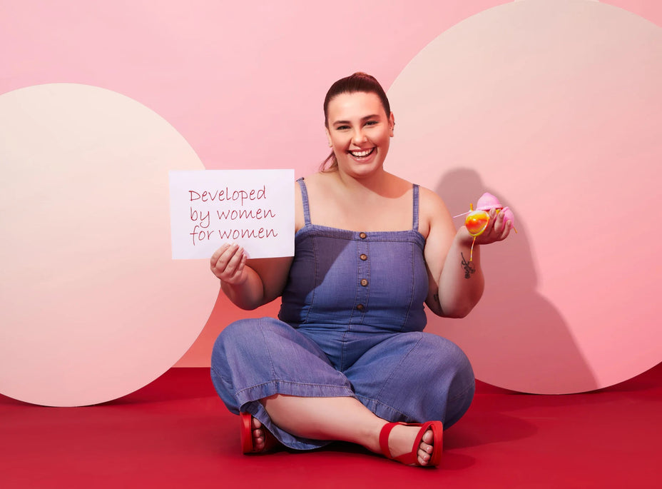 Woman with 3 menstrual discs in their right hand and holding a poster in the left hand written: Lumma is developed by women for women.